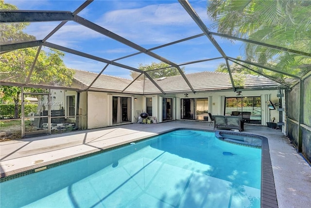 view of swimming pool featuring glass enclosure, ceiling fan, and a patio