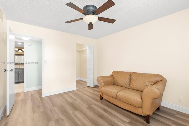 living area with ceiling fan, light hardwood / wood-style floors, and a textured ceiling