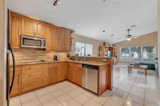 kitchen with kitchen peninsula, stainless steel appliances, vaulted ceiling, sink, and light tile patterned floors