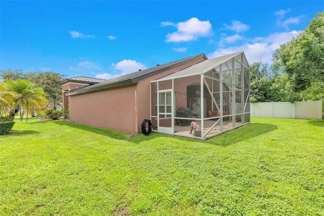 rear view of property with a lanai and a lawn