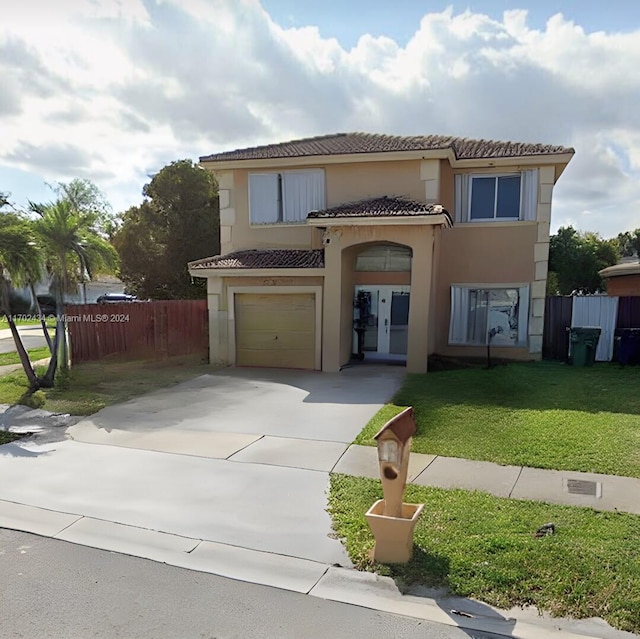 mediterranean / spanish house featuring a garage and a front lawn