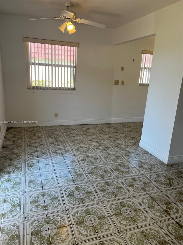 tiled empty room with plenty of natural light and ceiling fan