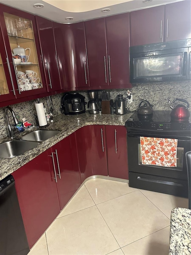 kitchen featuring light tile patterned floors, backsplash, dark stone countertops, black appliances, and sink