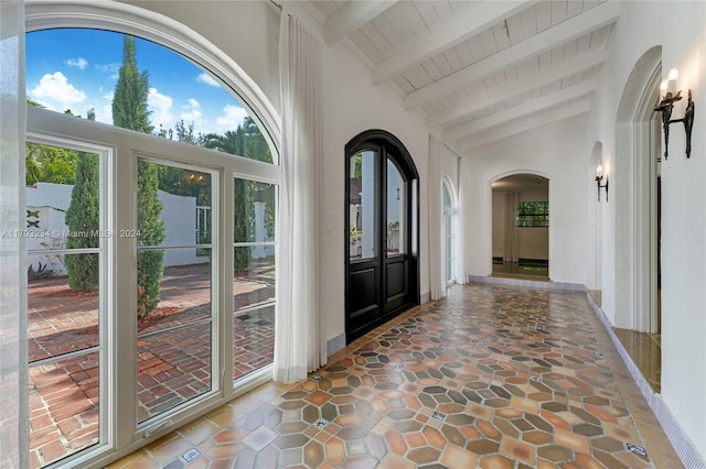 foyer entrance featuring vaulted ceiling with beams, wooden ceiling, and a healthy amount of sunlight