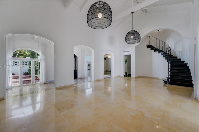 unfurnished living room with beam ceiling, high vaulted ceiling, and french doors