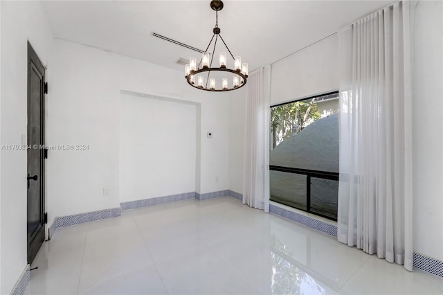 tiled spare room featuring a notable chandelier