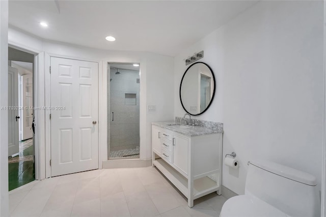 bathroom featuring tile patterned floors, vanity, toilet, and a shower with door