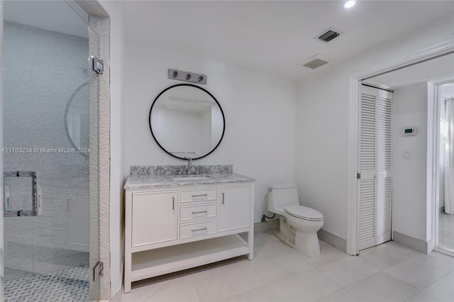 bathroom featuring a tile shower, tile patterned flooring, vanity, and toilet