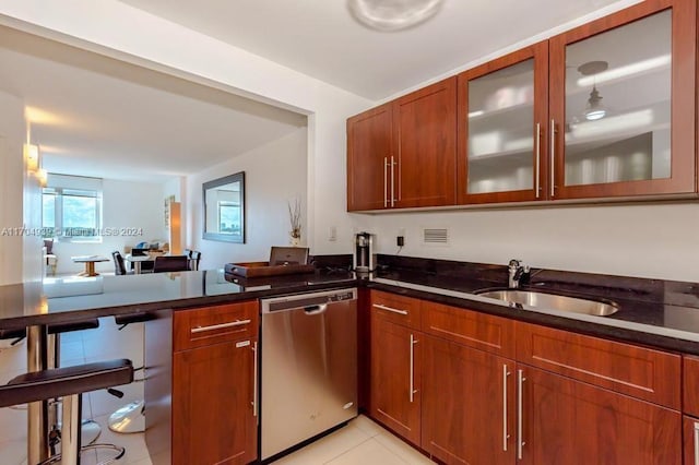 kitchen featuring dishwasher, light tile patterned floors, dark stone countertops, and sink