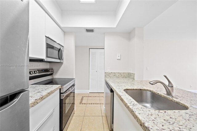 10001 W Atlantic Blvd Unit 316, Coral Springs, FL 33071 - kitchen featuring appliances with stainless steel finishes, light tile patterned floors, white cabinetry, light stone countertops, and a tray ceiling