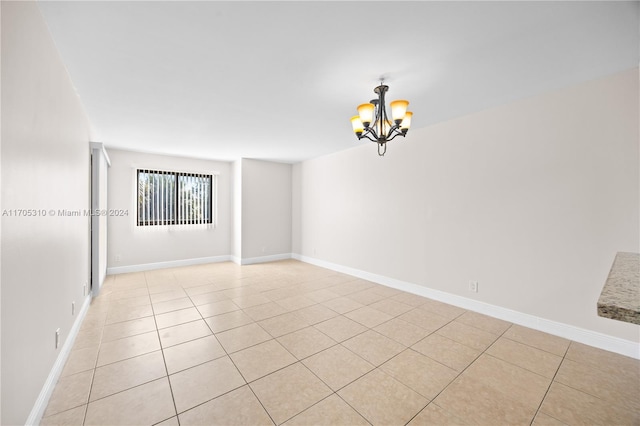 tiled empty room with a notable chandelier