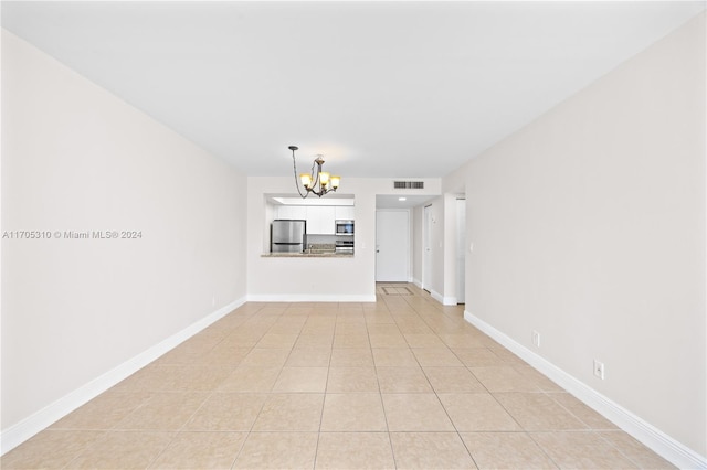 empty room featuring light tile patterned flooring and a chandelier