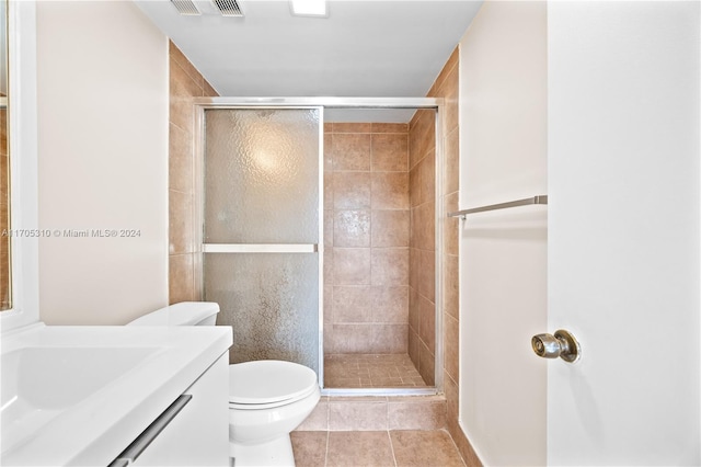 bathroom featuring toilet, vanity, tile patterned floors, and walk in shower