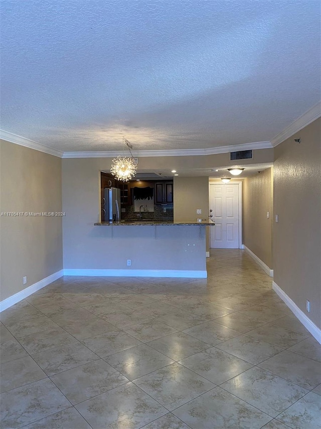 interior space with kitchen peninsula, a textured ceiling, stainless steel refrigerator, and ornamental molding