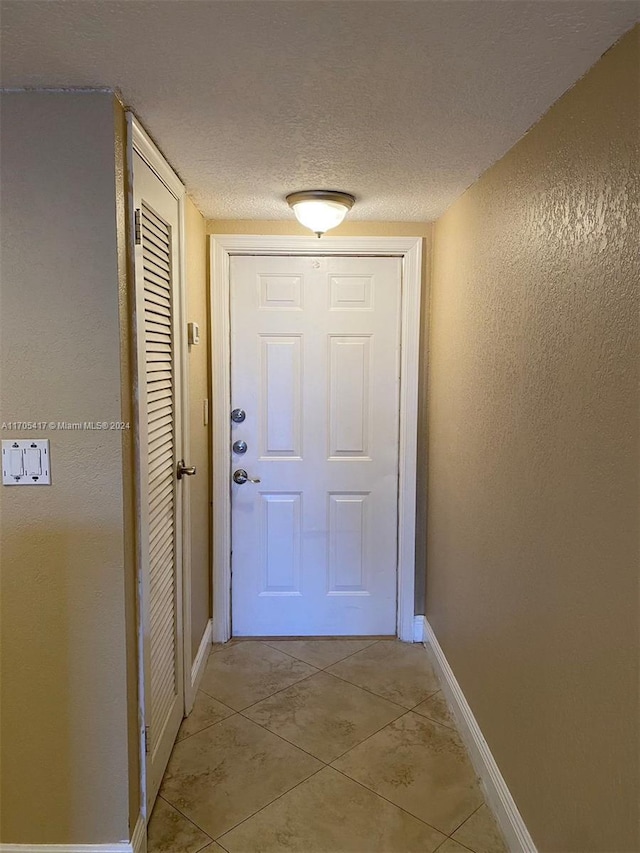 doorway with light tile patterned floors and a textured ceiling