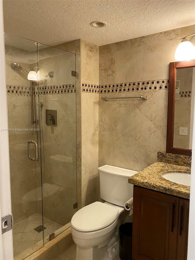 bathroom with vanity, toilet, an enclosed shower, and a textured ceiling