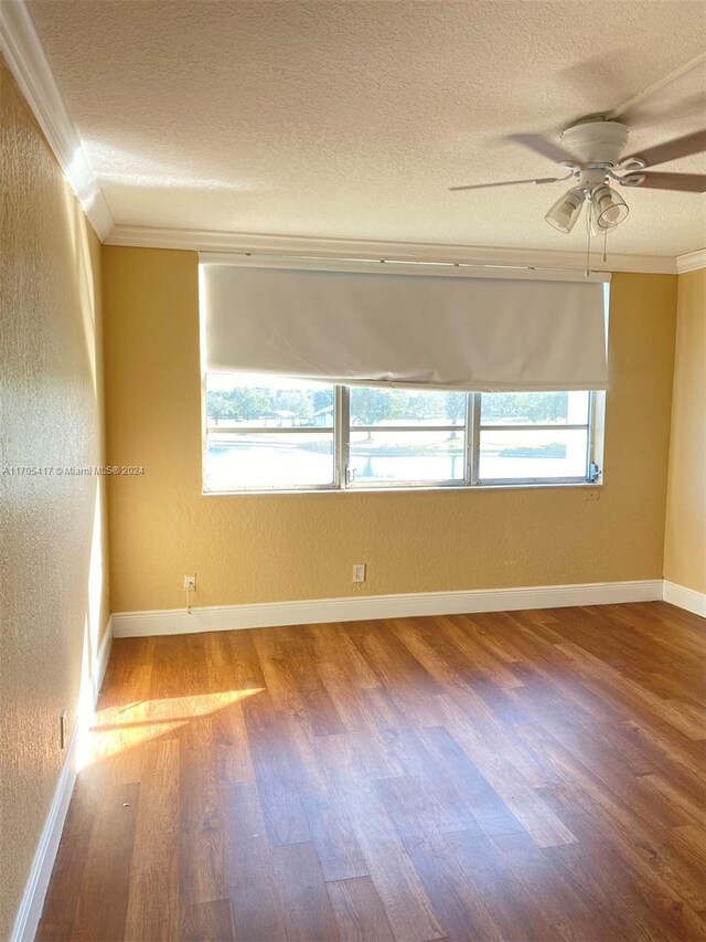 empty room featuring a textured ceiling, hardwood / wood-style flooring, ceiling fan, and crown molding