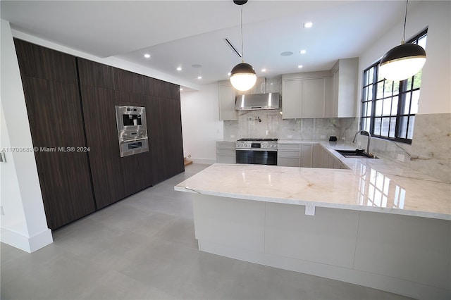 kitchen featuring kitchen peninsula, dark brown cabinets, stainless steel appliances, wall chimney range hood, and white cabinetry