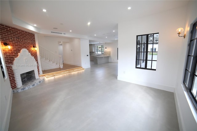 unfurnished living room featuring concrete floors and a brick fireplace