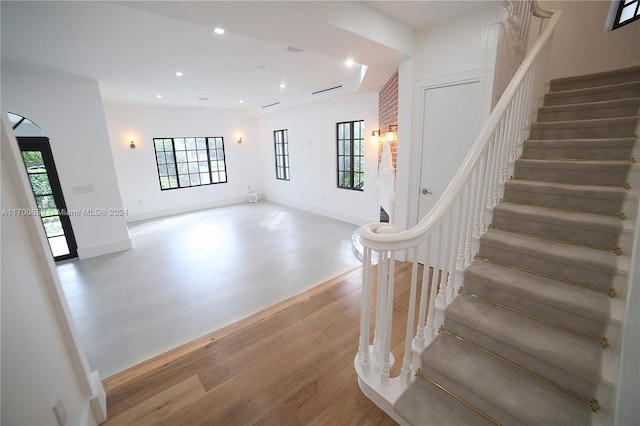 staircase with a healthy amount of sunlight and hardwood / wood-style flooring