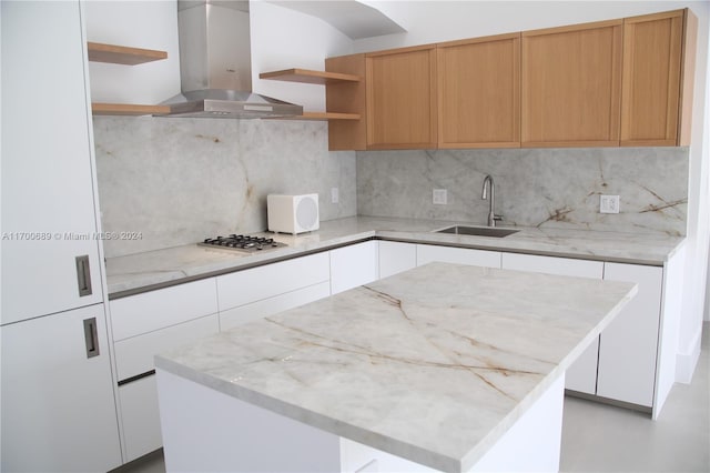 kitchen featuring white cabinets, sink, a kitchen island, light stone counters, and island exhaust hood