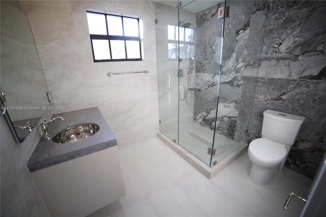 bathroom with an enclosed shower, vanity, tile walls, tile patterned flooring, and toilet