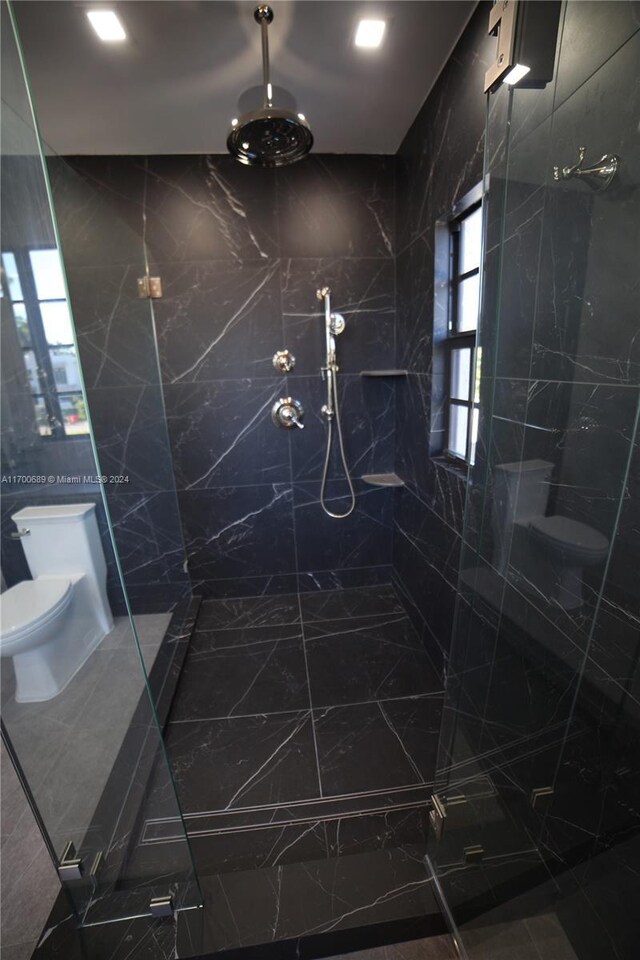 bathroom with a tile shower, tile walls, and toilet