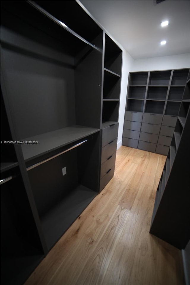 walk in closet with light hardwood / wood-style flooring