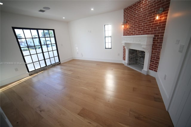 unfurnished living room featuring a fireplace, a wealth of natural light, and light hardwood / wood-style flooring