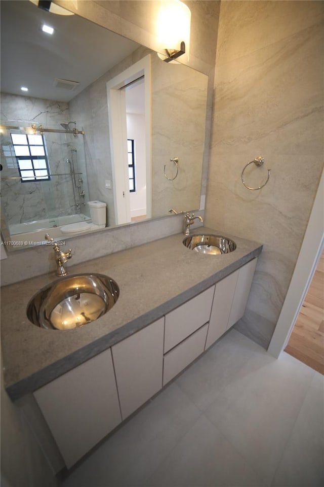 bathroom with vanity, toilet, tiled shower, and tile walls