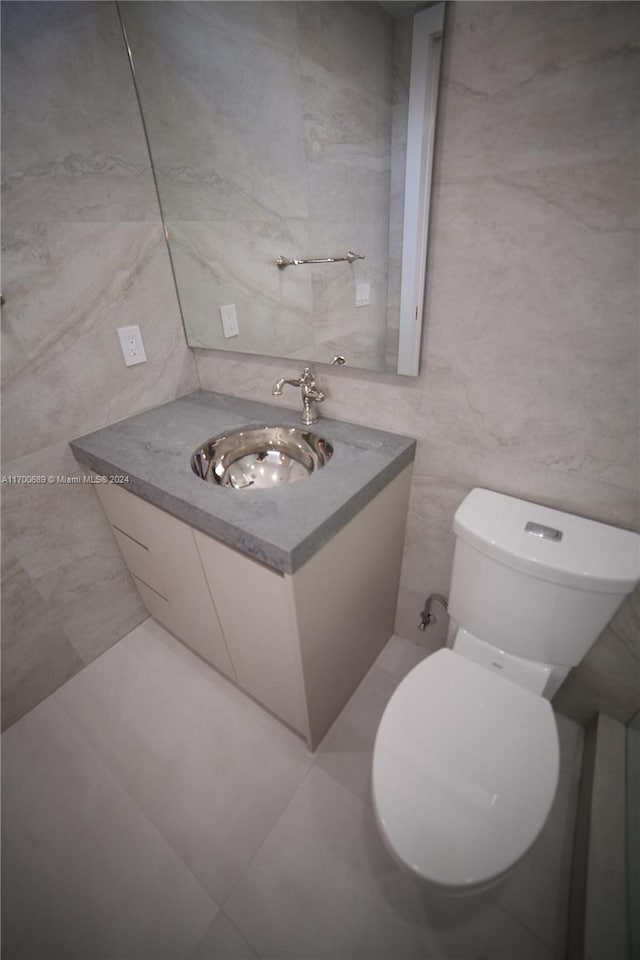 bathroom featuring tile patterned floors, vanity, tile walls, and toilet