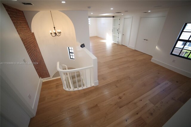 corridor featuring a chandelier and light hardwood / wood-style flooring