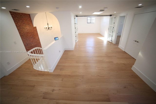 corridor with a chandelier and light hardwood / wood-style flooring