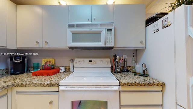 kitchen with light stone counters, white cabinets, and white appliances