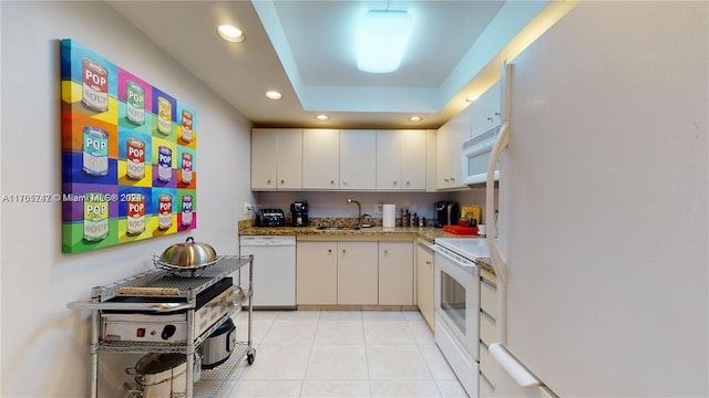 kitchen featuring white cabinets, a raised ceiling, white appliances, and sink