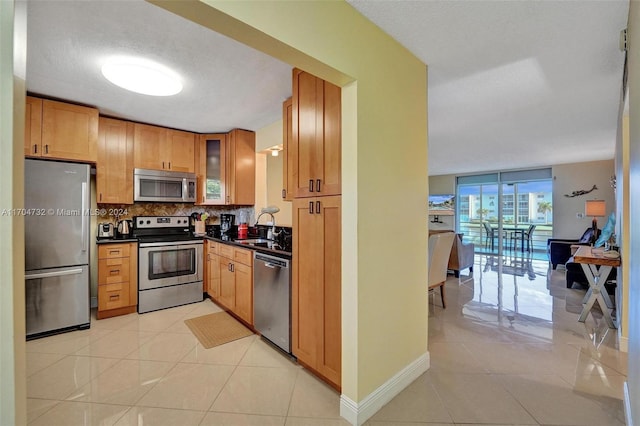 kitchen with decorative backsplash, sink, light tile patterned floors, and appliances with stainless steel finishes