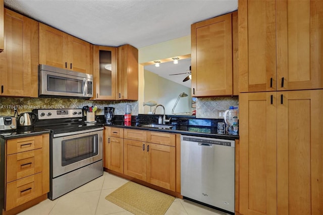 kitchen with ceiling fan, sink, decorative backsplash, light tile patterned floors, and appliances with stainless steel finishes