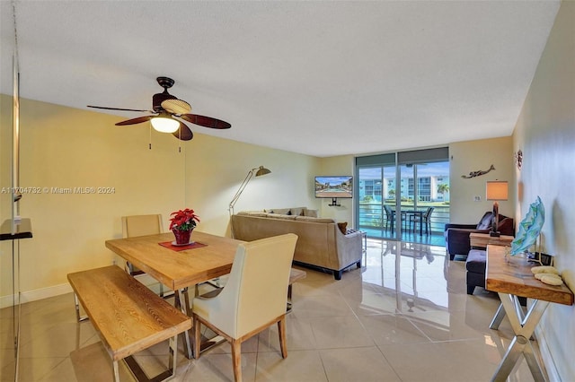 dining space featuring ceiling fan, light tile patterned flooring, a wall of windows, and a textured ceiling