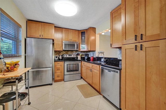 kitchen featuring decorative backsplash, appliances with stainless steel finishes, light tile patterned floors, and sink