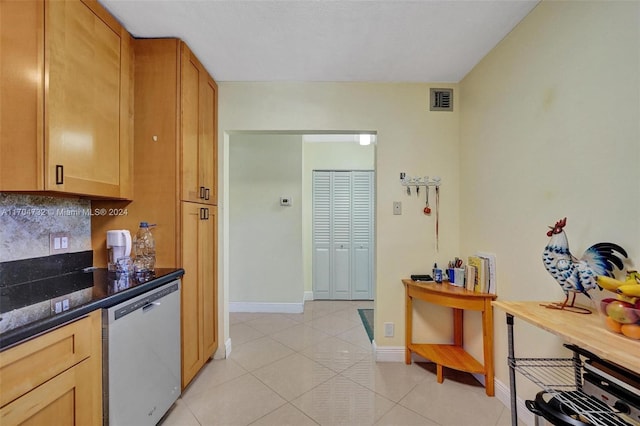 kitchen featuring light tile patterned floors, tasteful backsplash, stainless steel dishwasher, and dark stone counters