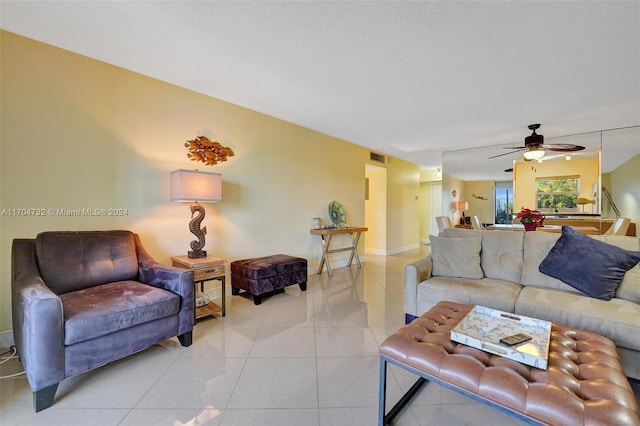 living room with ceiling fan, light tile patterned floors, and a textured ceiling