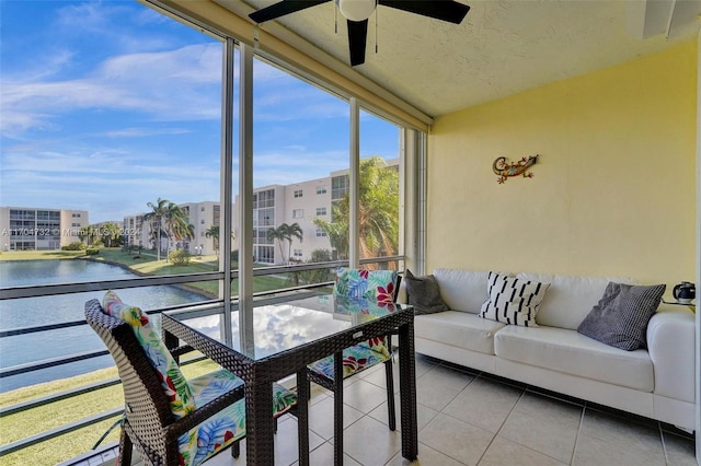 sunroom with ceiling fan and a water view