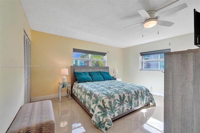 bedroom featuring ceiling fan, light tile patterned flooring, and a textured ceiling