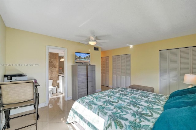 bedroom featuring multiple closets, ceiling fan, light tile patterned floors, and ensuite bathroom