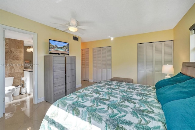 tiled bedroom featuring connected bathroom, two closets, ceiling fan, and tile walls