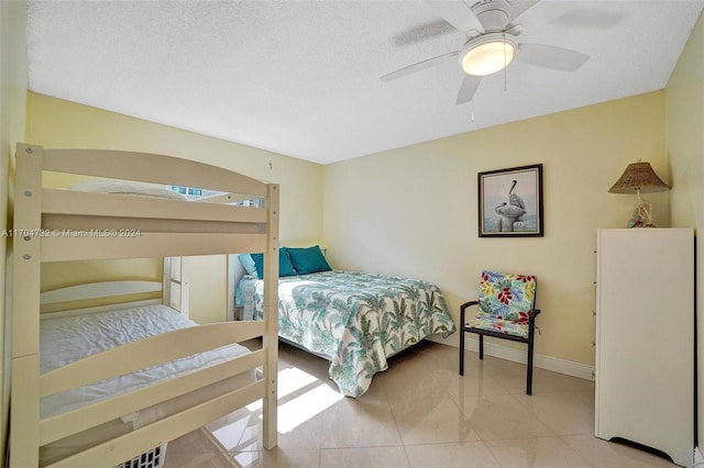 bedroom with ceiling fan, light tile patterned floors, and a textured ceiling