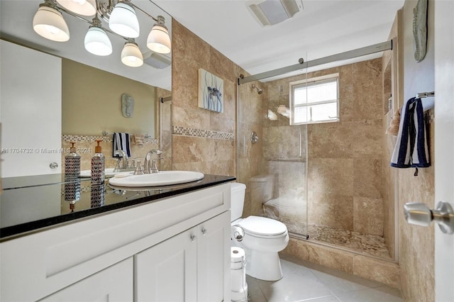 bathroom featuring tile patterned floors, vanity, a shower with door, tile walls, and toilet