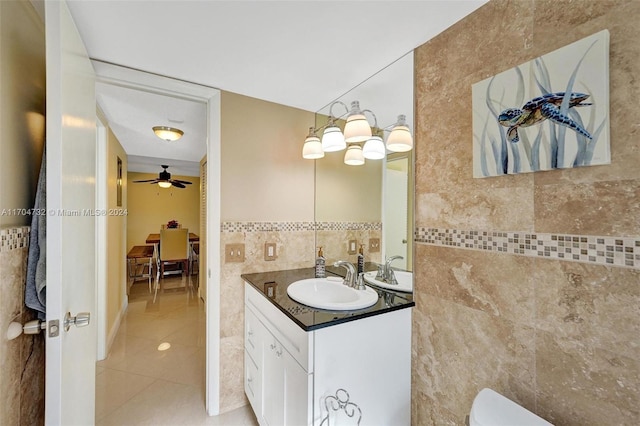 bathroom with ceiling fan, tile patterned flooring, toilet, vanity, and tile walls