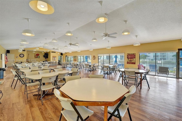 dining space featuring a textured ceiling, light hardwood / wood-style flooring, ceiling fan, and lofted ceiling