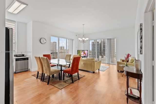 dining area with light wood-type flooring and an inviting chandelier